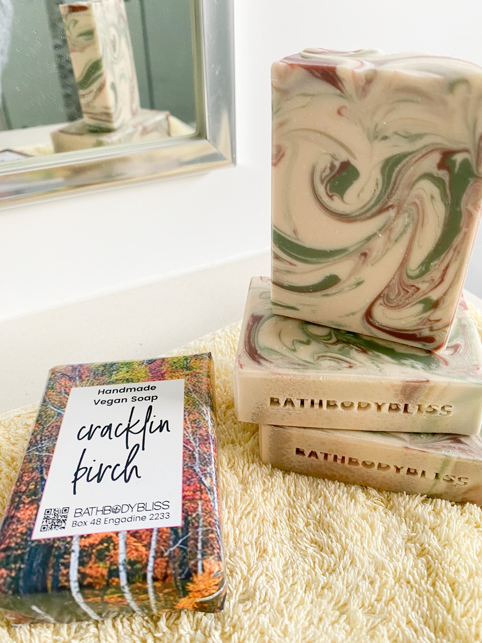 three swirled unwrapped soap bars and a wrapped cracklin birch soap bar on a yellow towel
