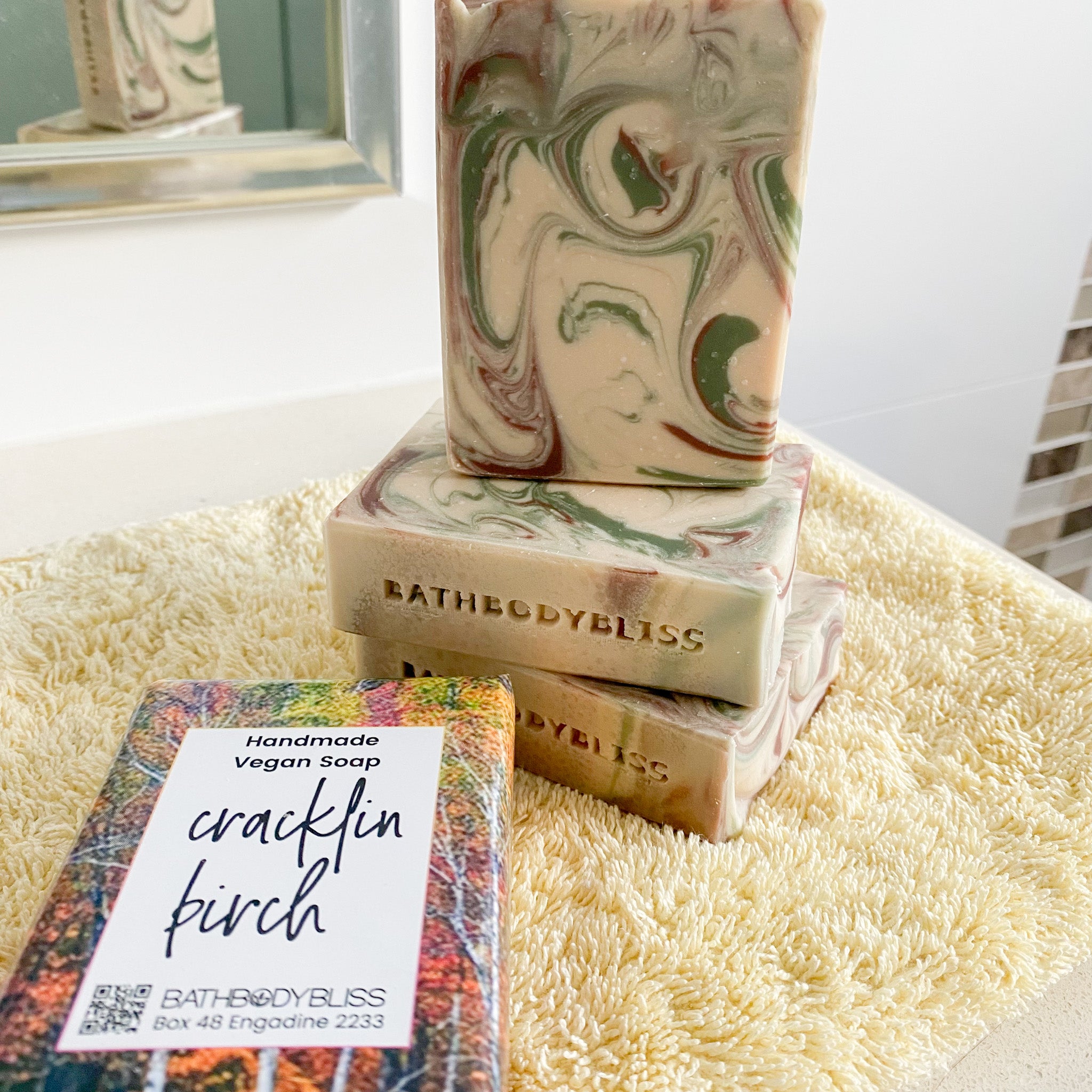 three forest coloured swirled soap bars with a cracklin birch wrapped soap on a yellow towel