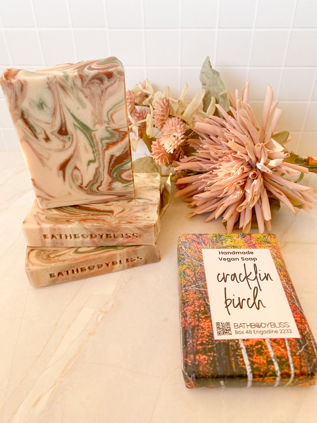 three unwrapped soap bars and a wrapped soap bar on a light background with floral decor