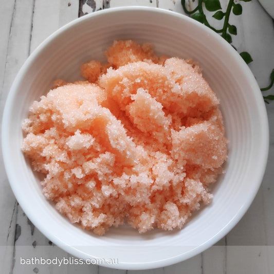 white bowl filed with pale orange sugar bodyscrub, on a pale background