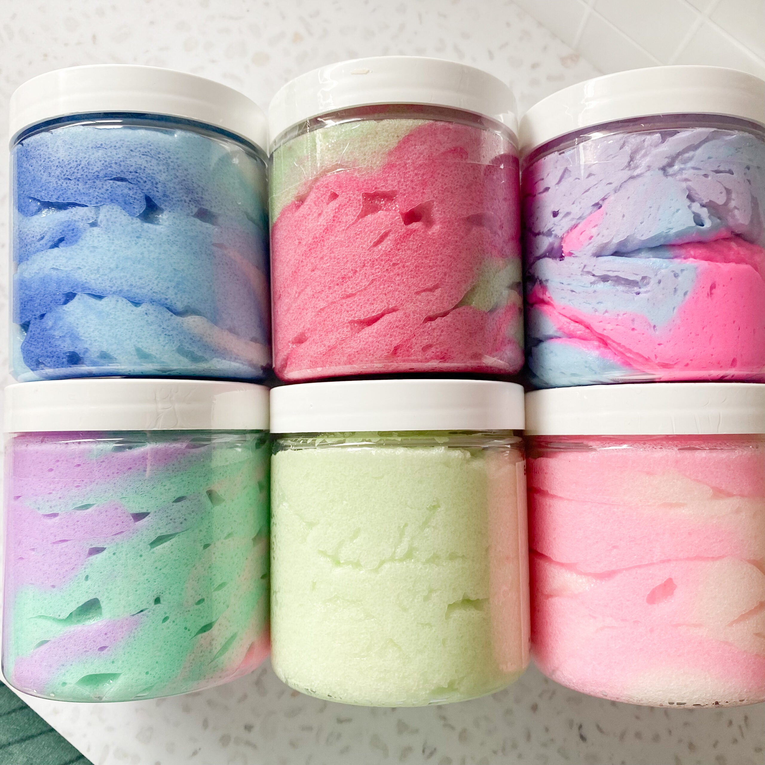 six jars of colourful body scrub