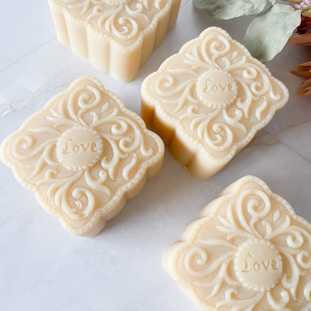 Decorative soap bars with intricate designs and 'love' embossing on a light surface.