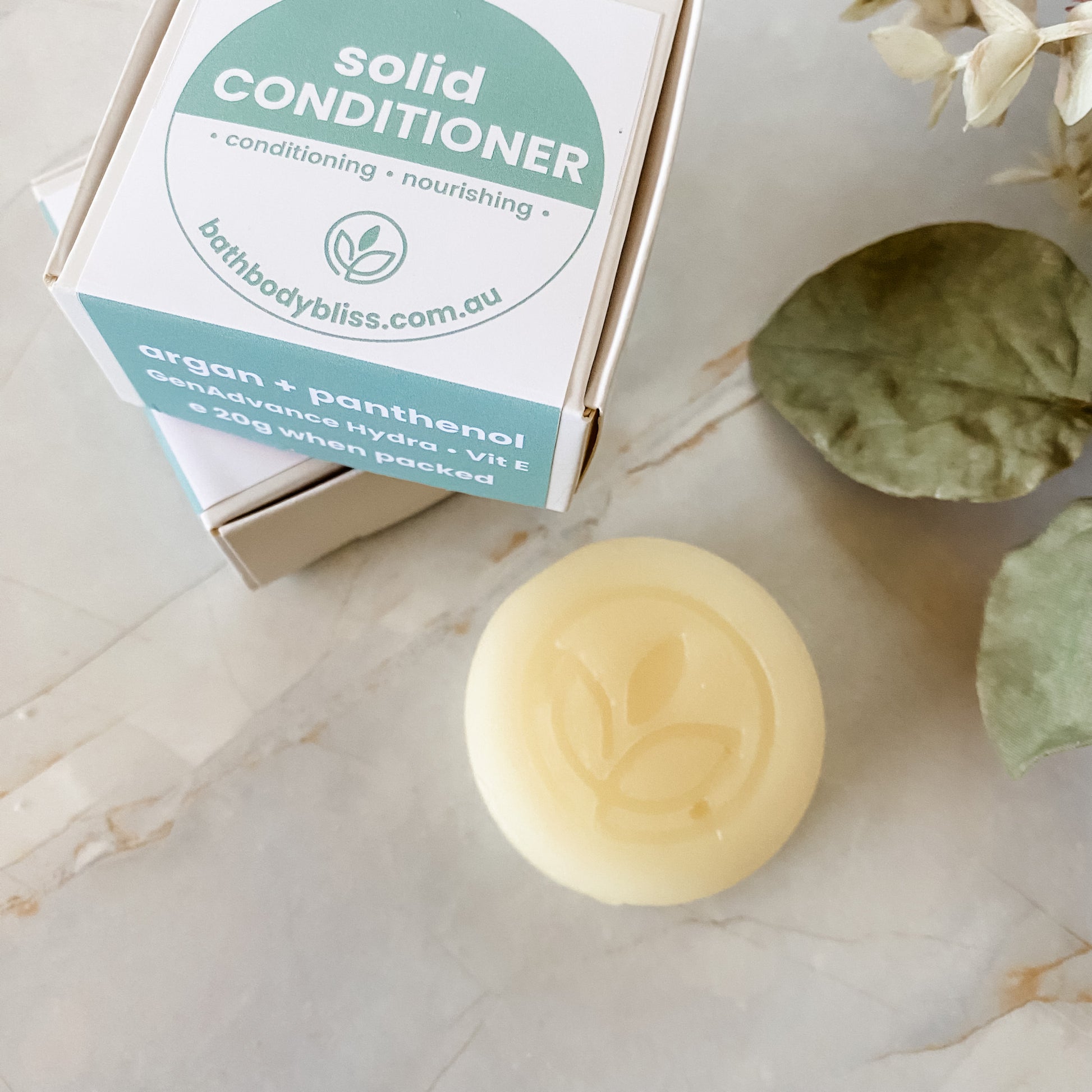 Solid conditioner bar with packaging on a marble surface