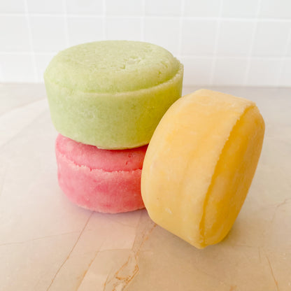 Three colorful shampoo bars stacked on a marble surface
