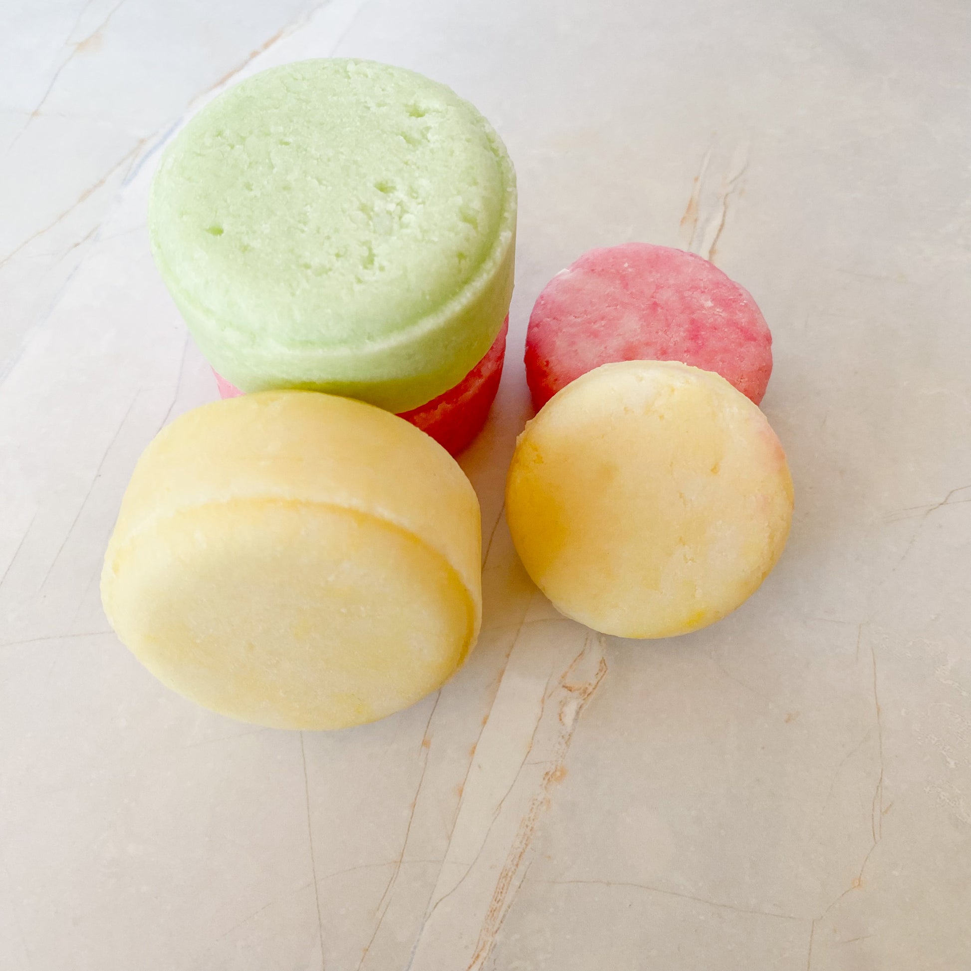 small and large shampoo bars on a marble surface