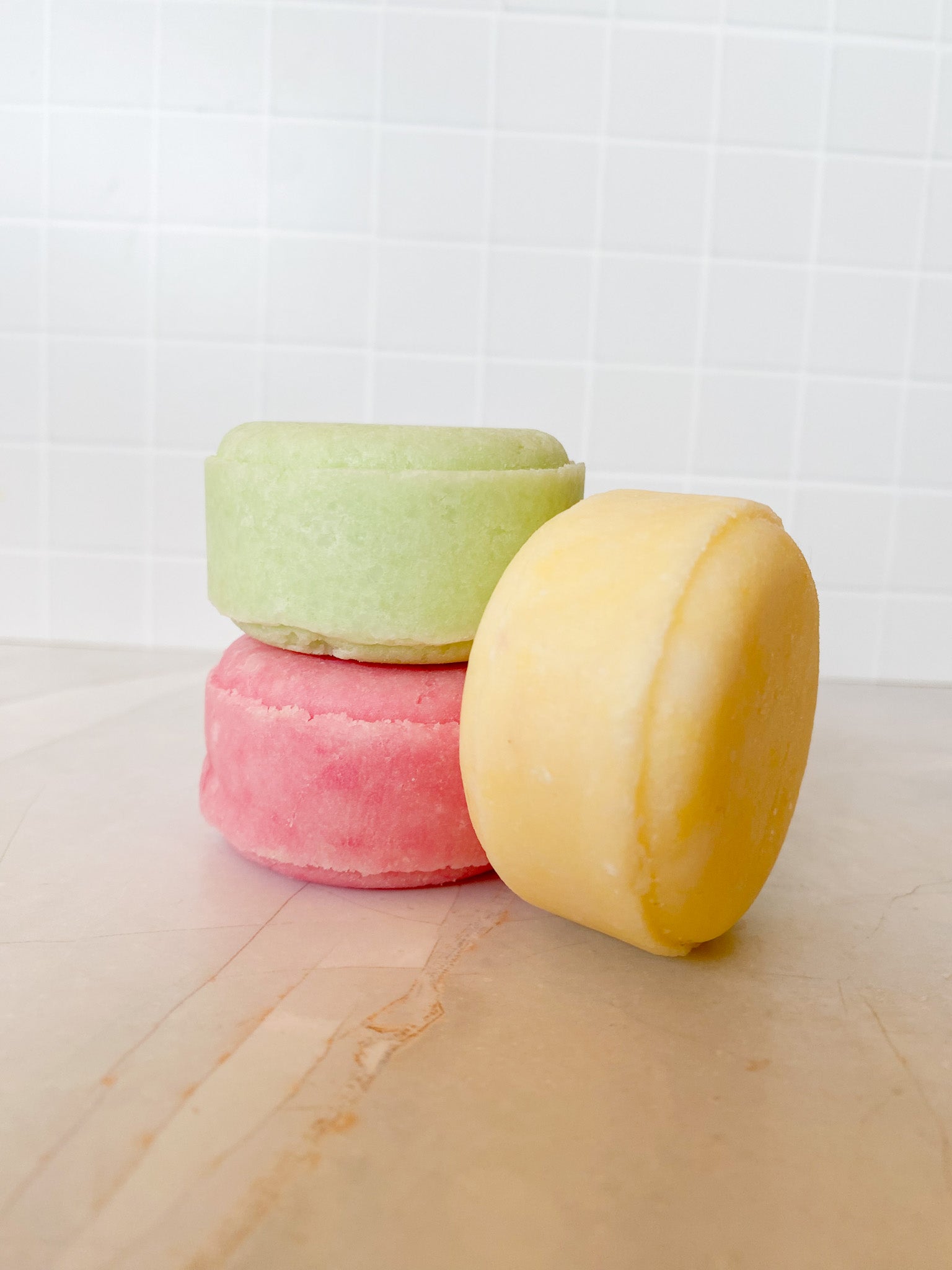 Three colorful shampoo bars on a marble surface with a white background