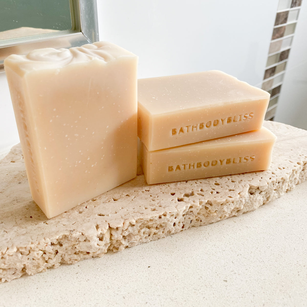 Three bars of Bathbody Bliss soap on a stone surface with a neutral background.
