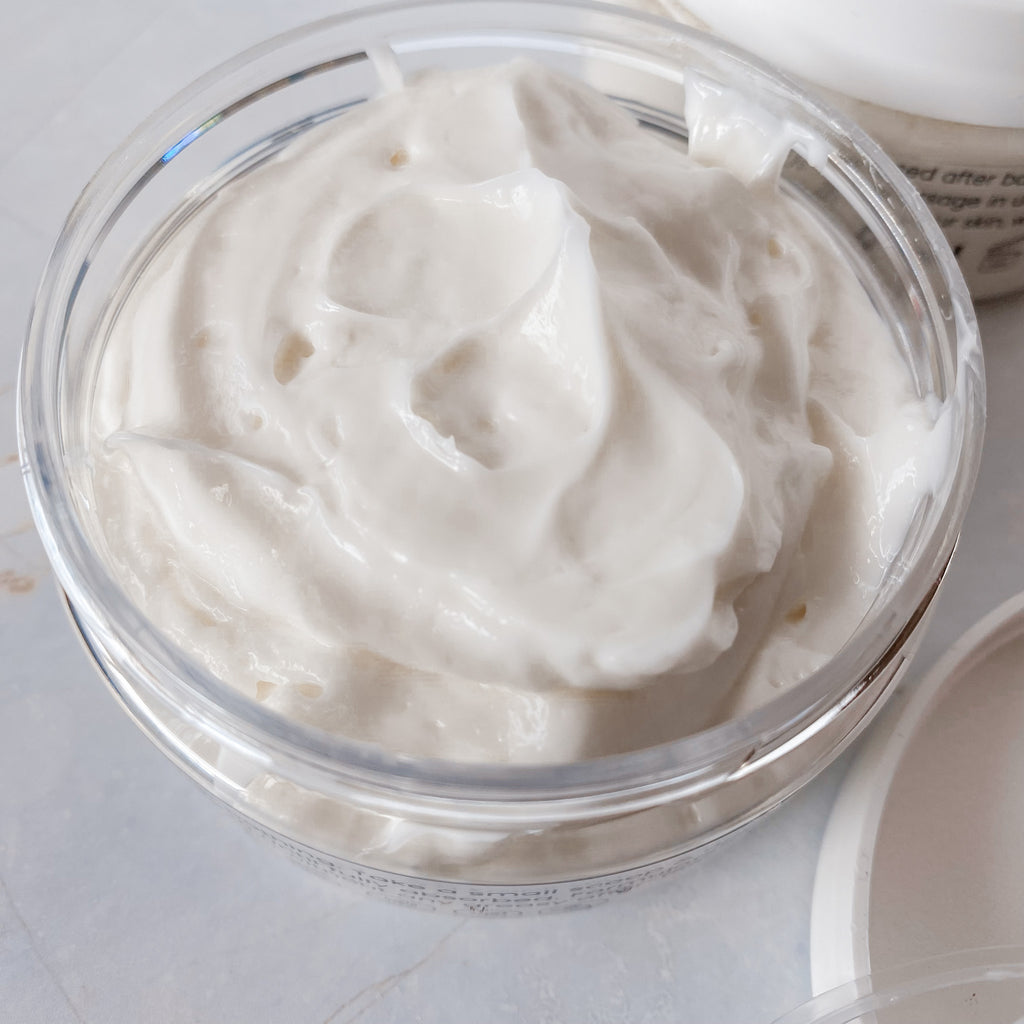 opened jar of thick, white body butter on a pale background