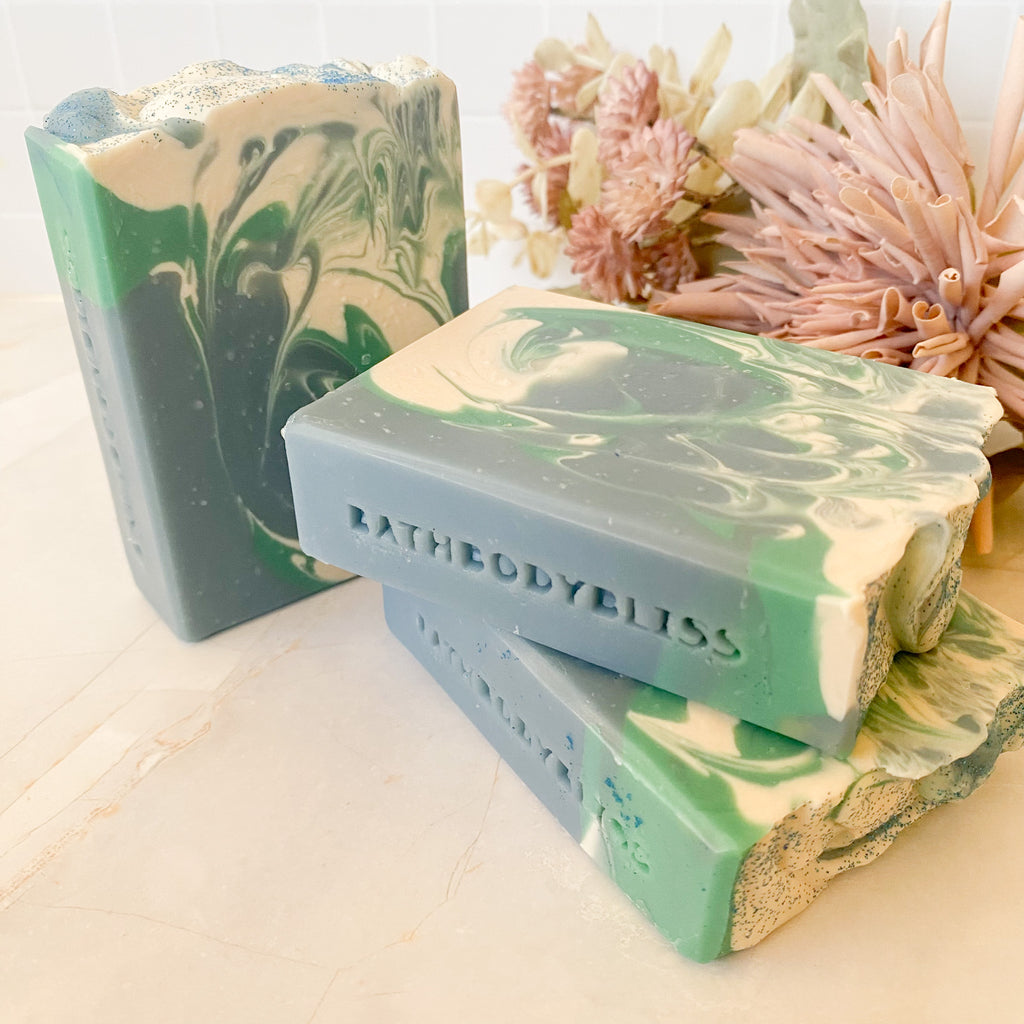 swirled blue, green and white soap bars with 'BathBodyBliss' branding on a light surface.