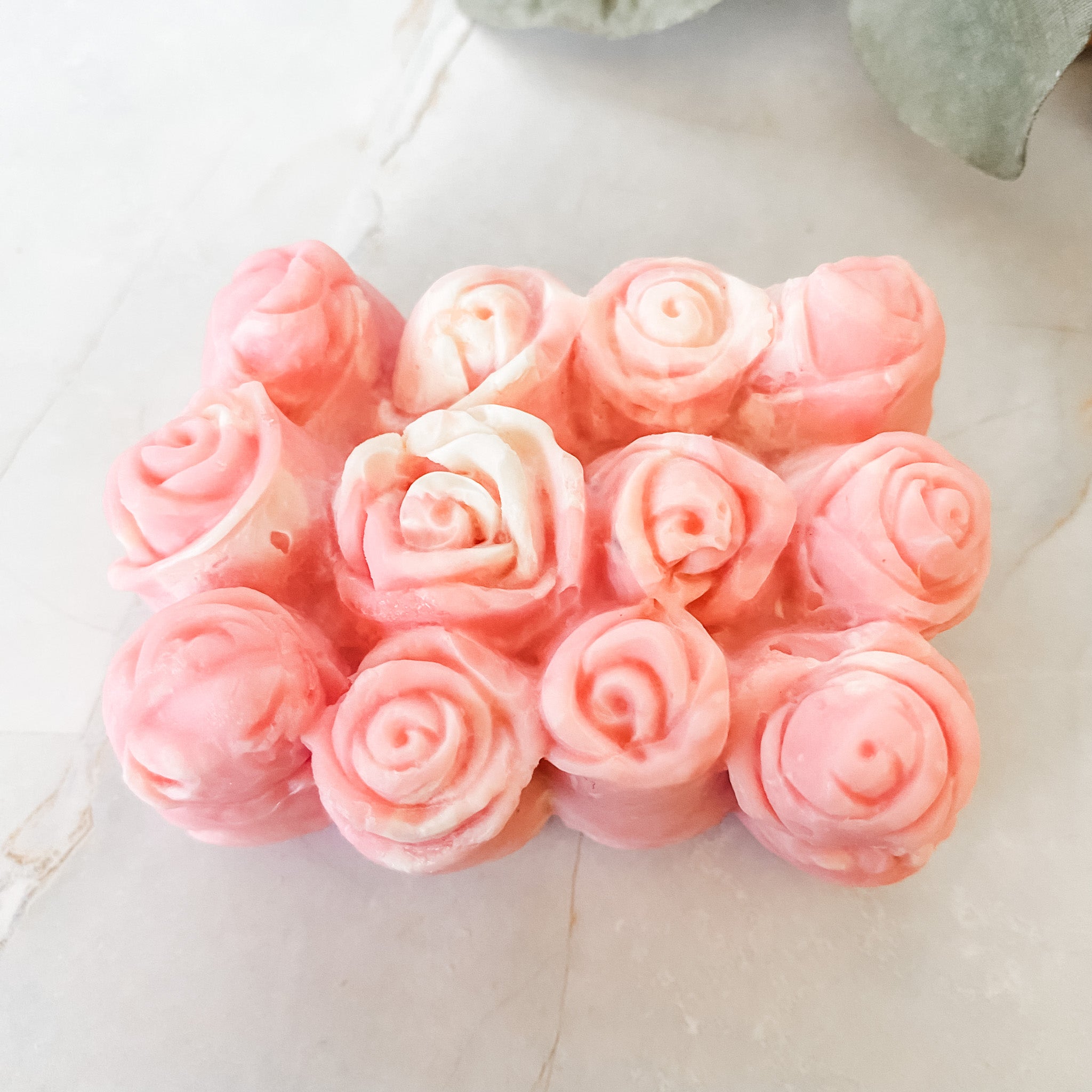 Pink rose-shaped soap bars on a light marble surface