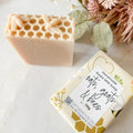 soap with honeycomb and bee impression on light surface with wrapped soap beside