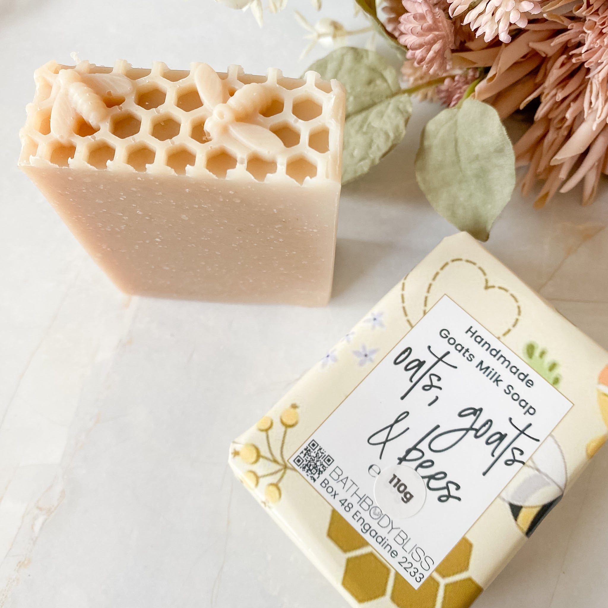 soap with honeycomb and bee impression on light surface with wrapped soap beside