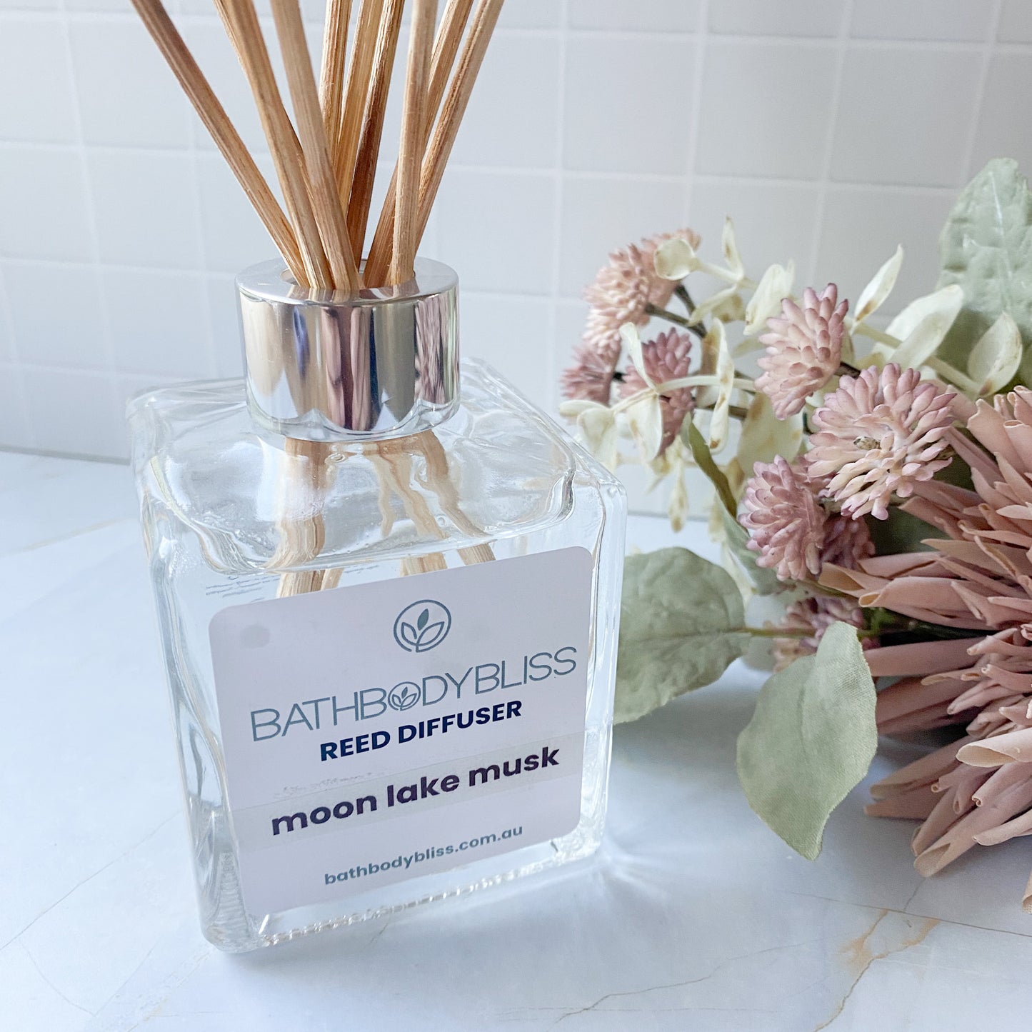 Cube glass  Reed diffuser labeled 'BathBodyBliss' with flowers on a white surface