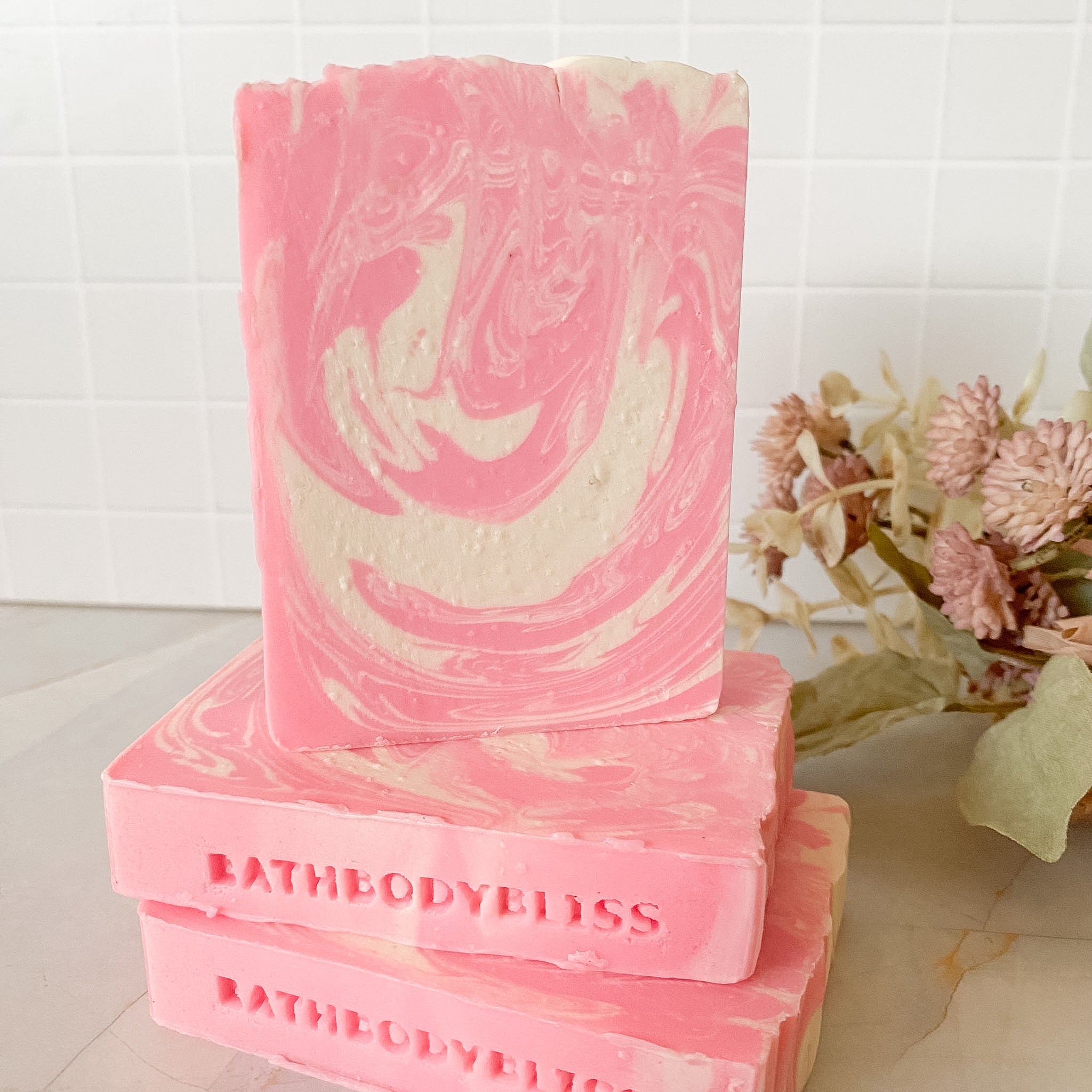 Pink and white swirled soap with 'BathBodyBliss' branding on a light background.