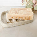 Marble-patterned soap bar with 'BATHBODYBLISS' branding on a speckled ceramic soap dish.