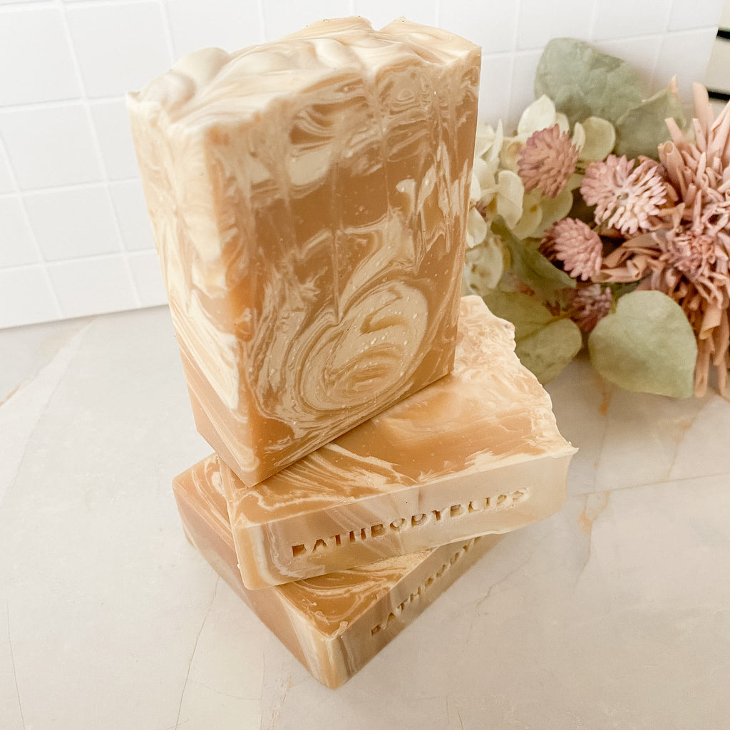 Three stacked soap bars with a marbled design on a llight surface with decorative flowers.